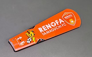 畳まれた状態のクラッカー。全体はオレンジ色をしている。クラッカーにはレノ丸および、「RENOFA YAMAGUCHI FC」、エンブレムがプリントされている。